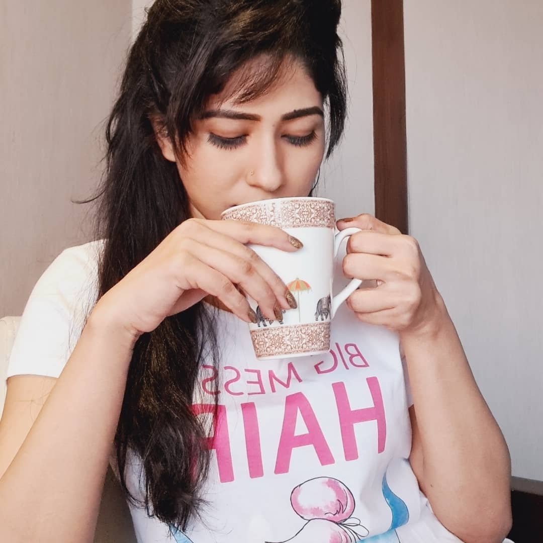 Angel Bhandari sipping coffe in white cup