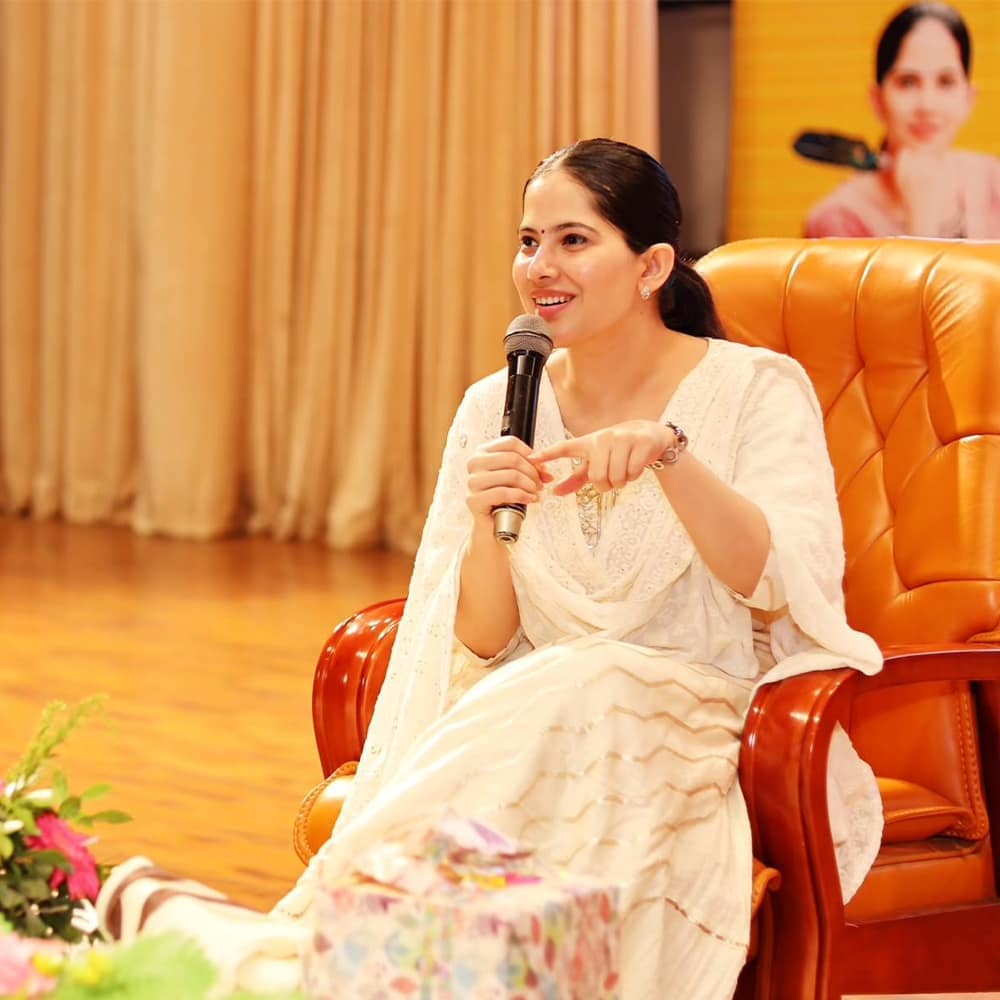 Jaya Kishroi in white dress addressing audience