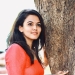 Aparna Das standing against a tree in red dress