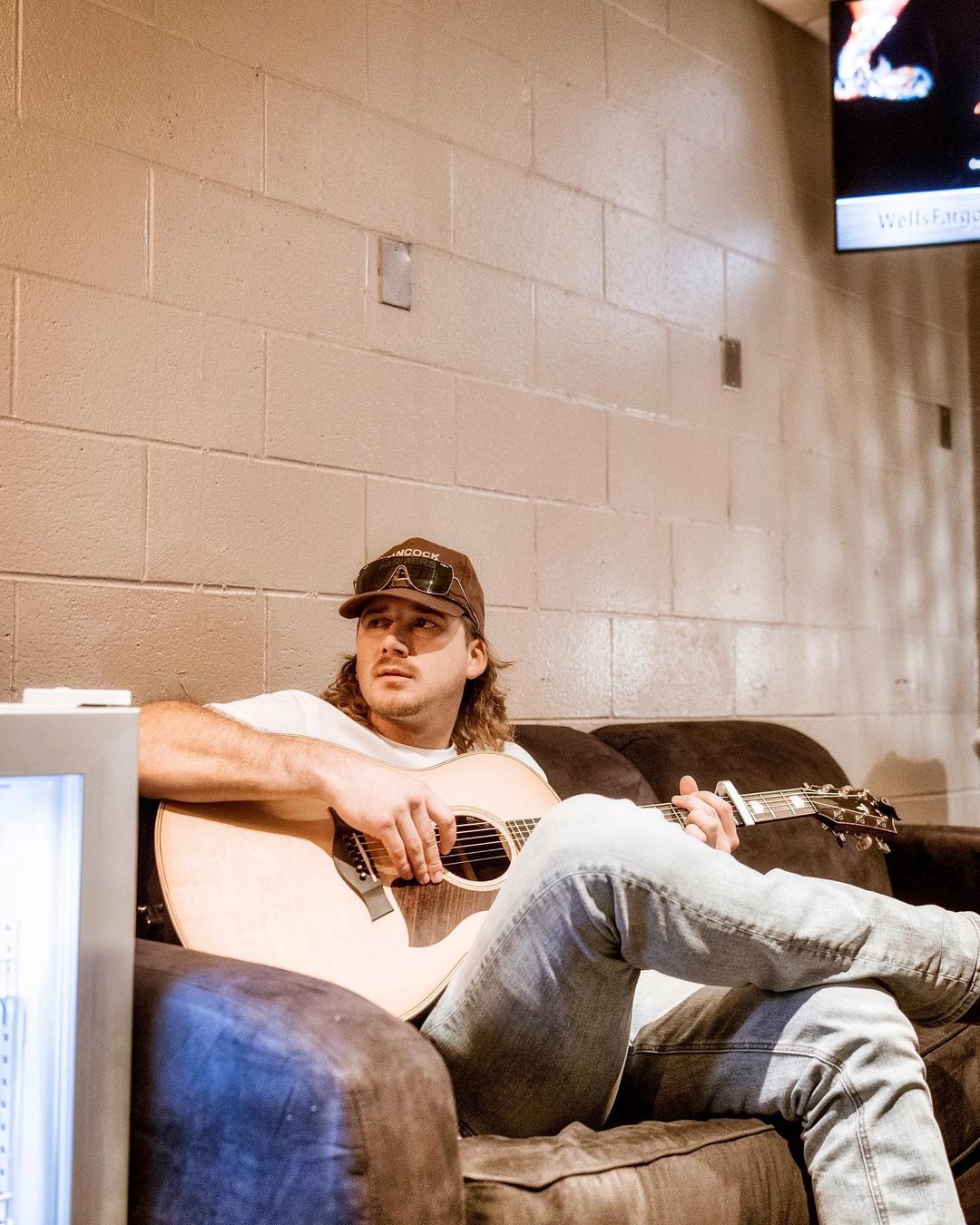 Morgan Wallen playing guitar in white t-shirt and blue jeans