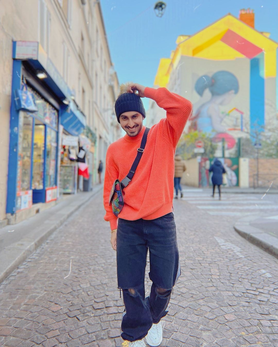 Rohanpreet Singh in orange sweatshirt and navy blue ripped jeans