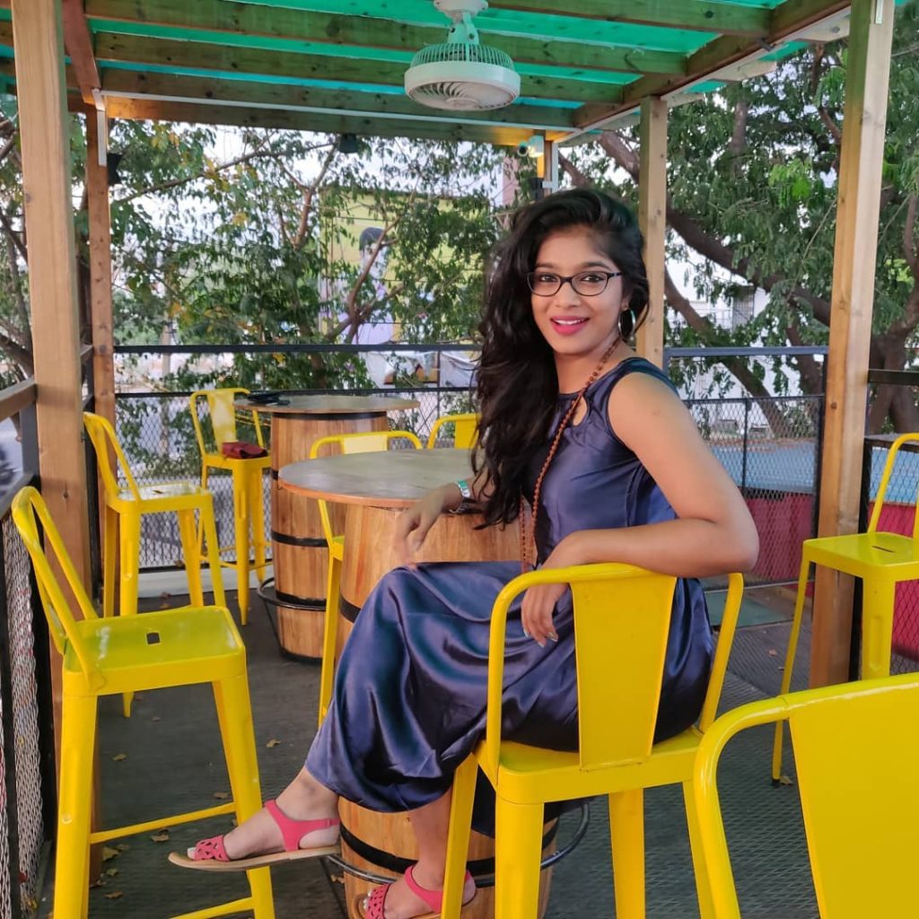 VJ Pavathy sitting on a yellow chair in purple dress