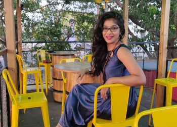 VJ Pavathy sitting on a yellow chair in purple dress