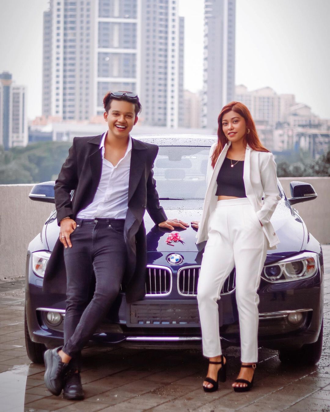 Riyaz Ali and Riza Afreen posing with a black BMW car