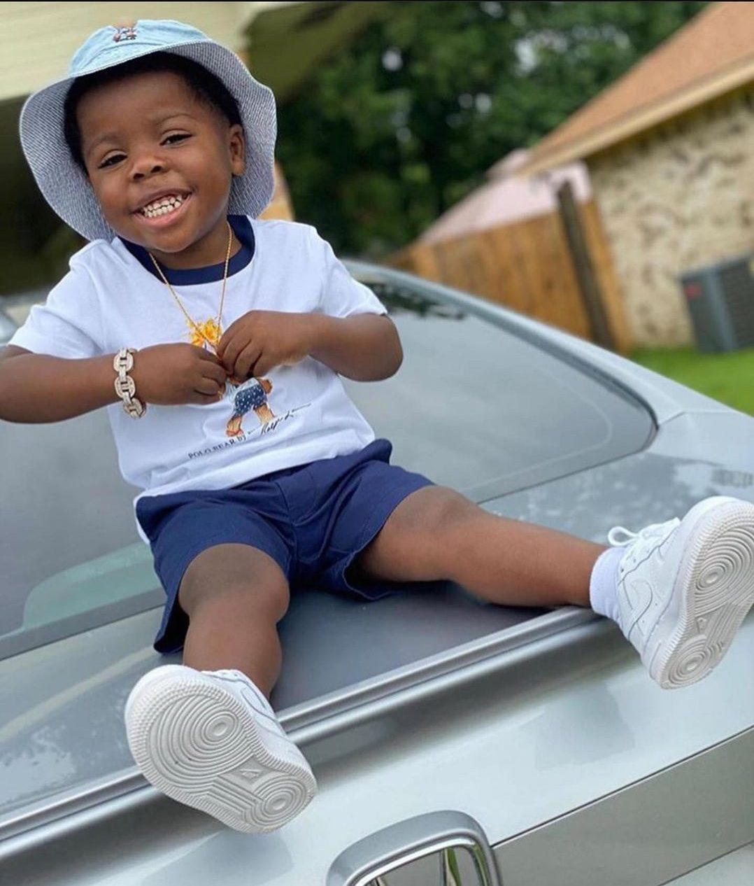 Kamiri Gaulden sitting on a car in white t-shirt and blue shorts