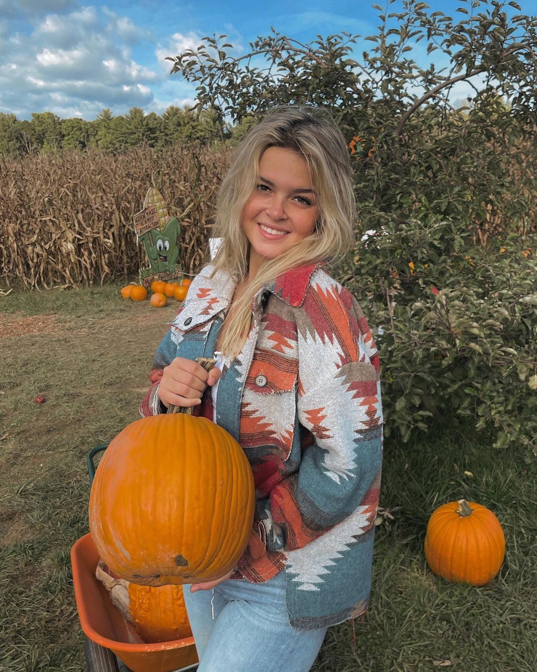 Kayla Patterson in geo print jacket holding a pumpkin