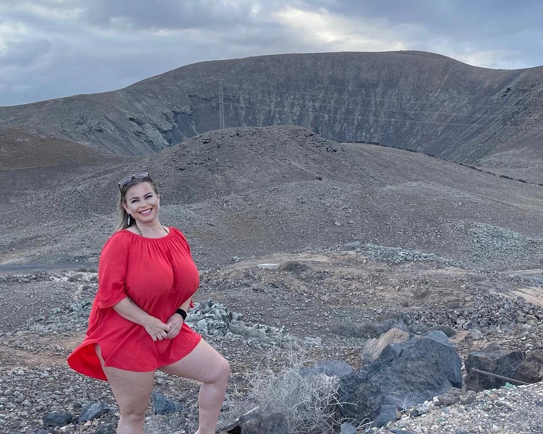 Bella Bodhi posing in red single piece dress near the crater of a volcano 