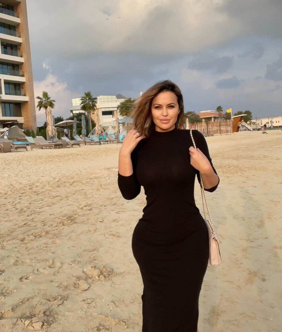Andrea Abeli in black dress enjoying on a beach.