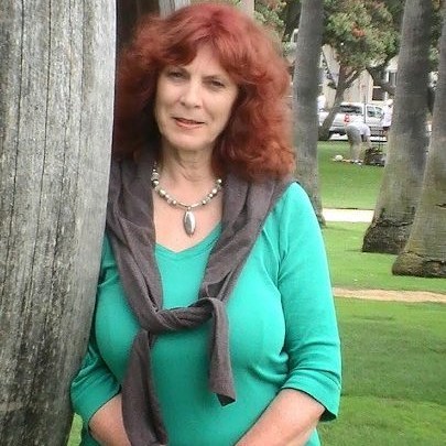 Kay Parker in green top standing with a tree 