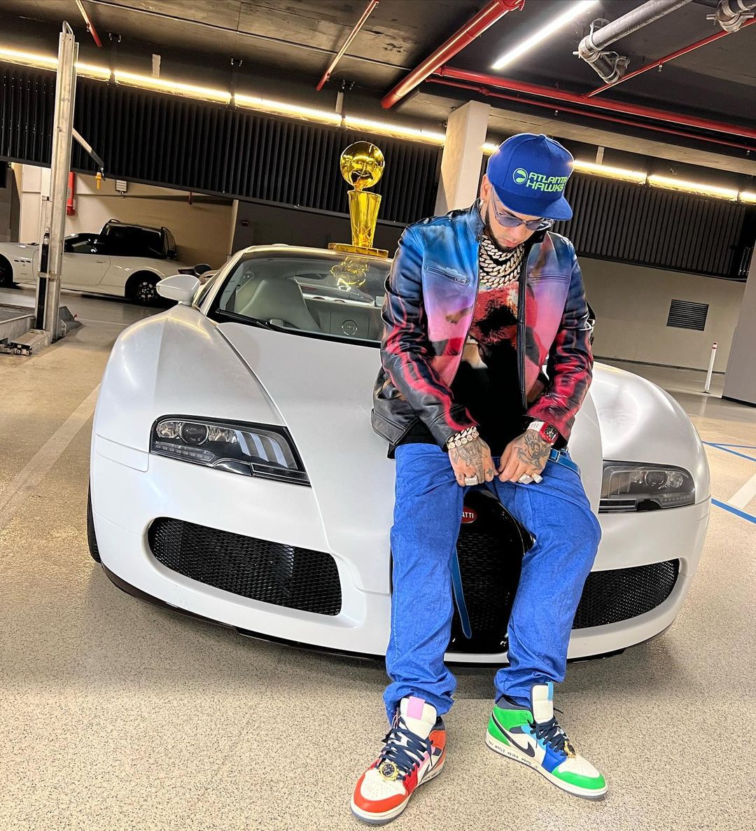 Anuel AA posing with a white luxury car