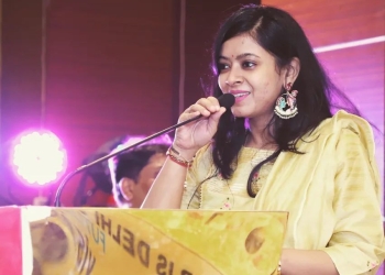 Tanu Jain addressing an event in yellow dress
