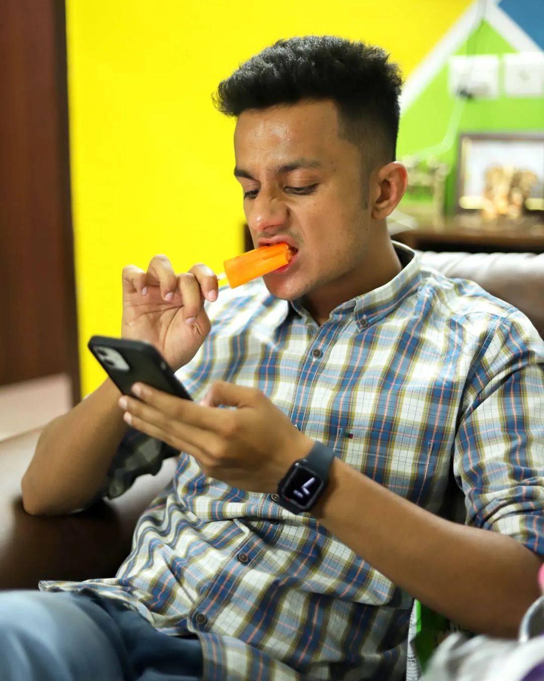 MBA Chai Wala eating orange bar while scrolling his phone