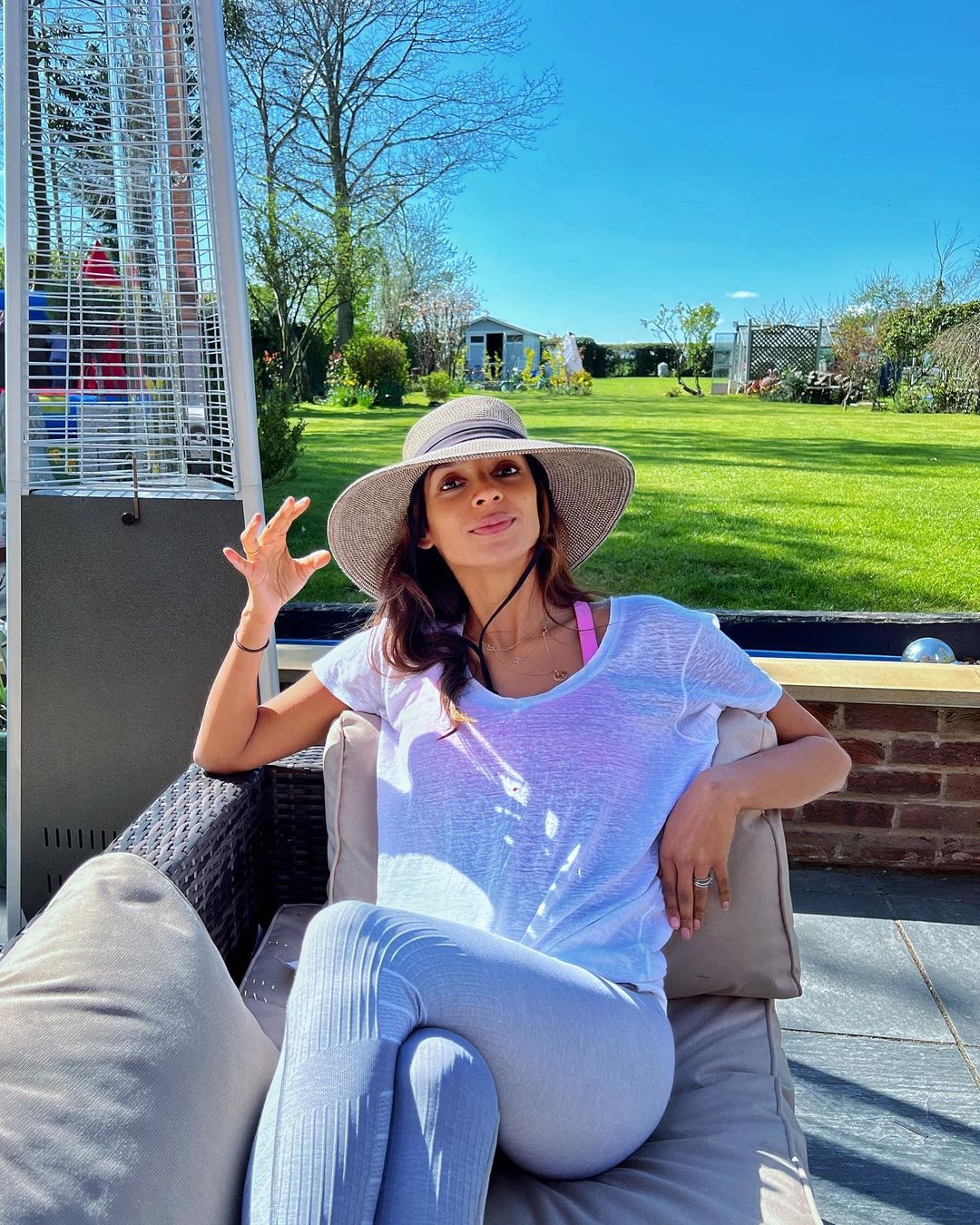 Shivi Ramoutar sitting on a sofa in white t-shirt and grey leggings